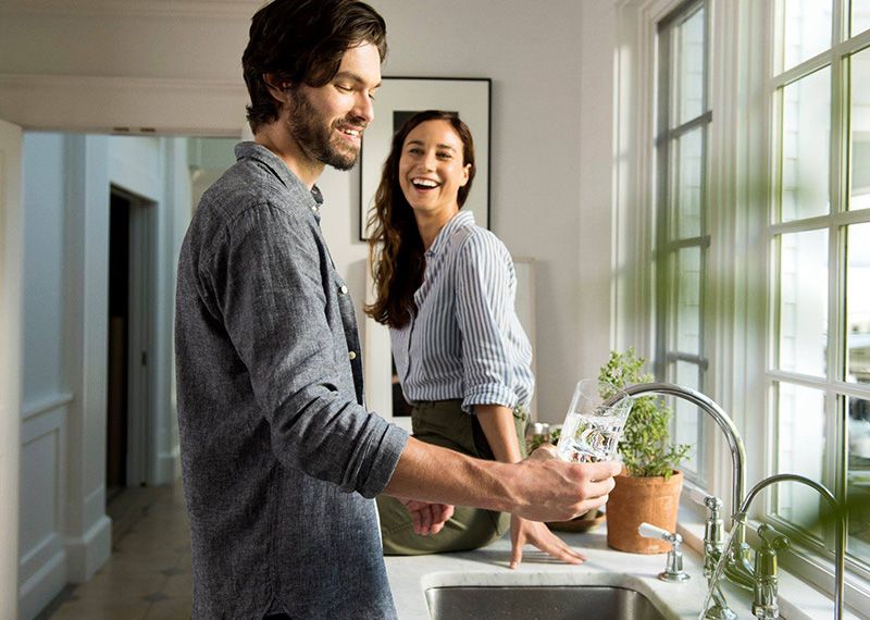 Man and Women getting water from a sink faucet