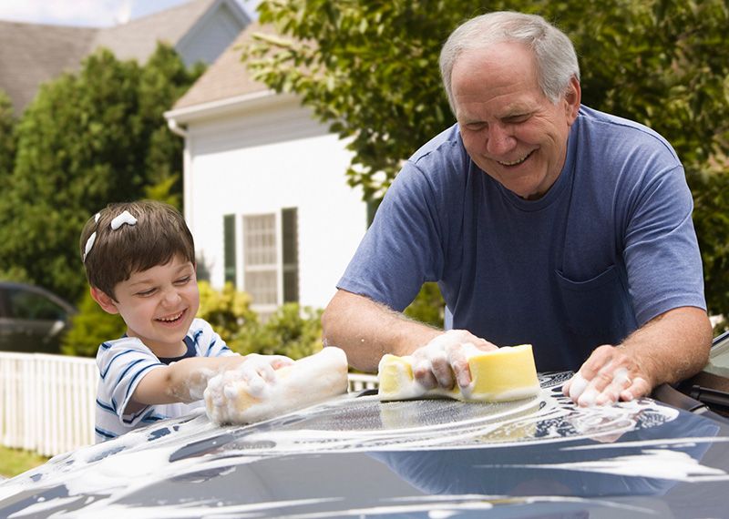 Grandfather and Grandson washing a car happily