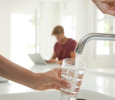 person filling drinking glass with water from tap