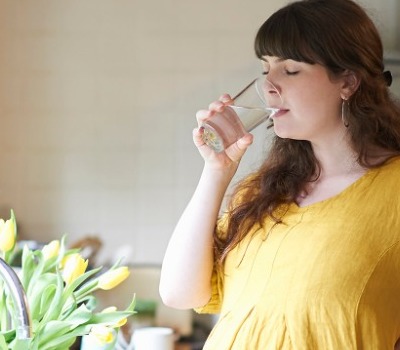 pregnant woman drinking water at sink