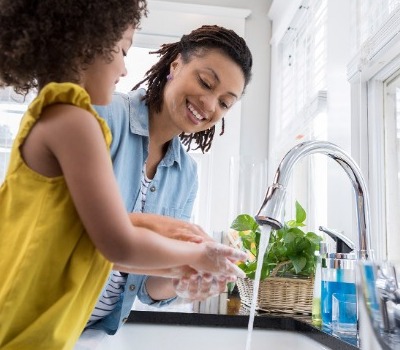 mother and daughter washing hands at sink